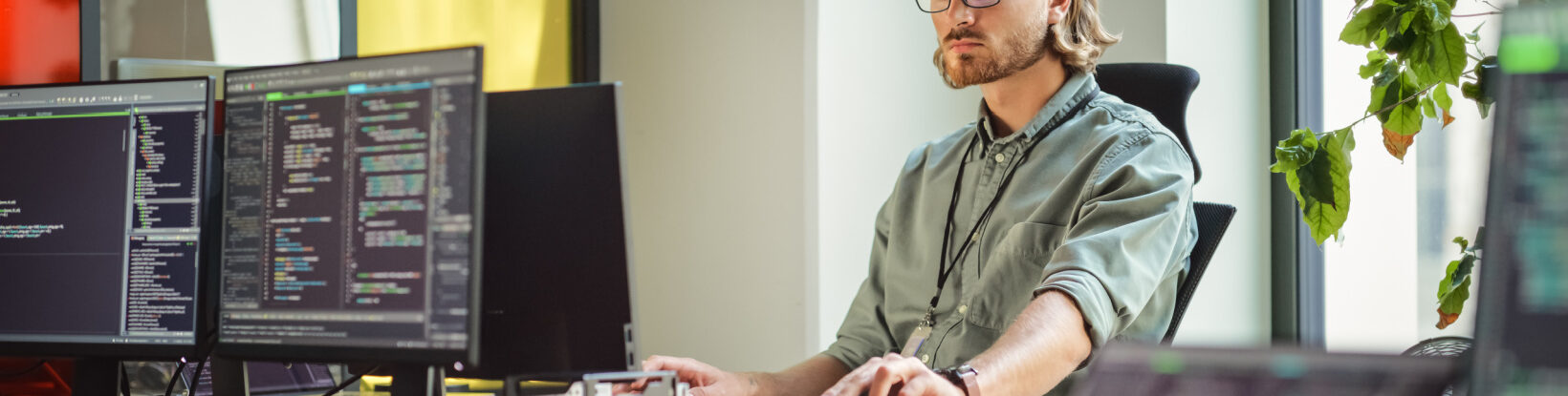 Young man sitting at computer using code.