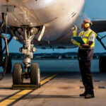 Man standing next to a plane on a runway.