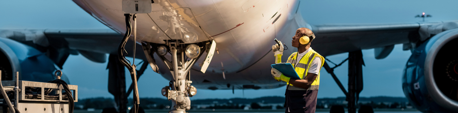 Man standing next to a plane on a runway.