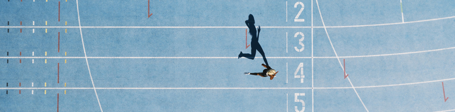 Overhead view of a single runner sprinting on a blue track, casting a long shadow across numbered lanes, symbolizing speed, progress, and accelerated data modernization.